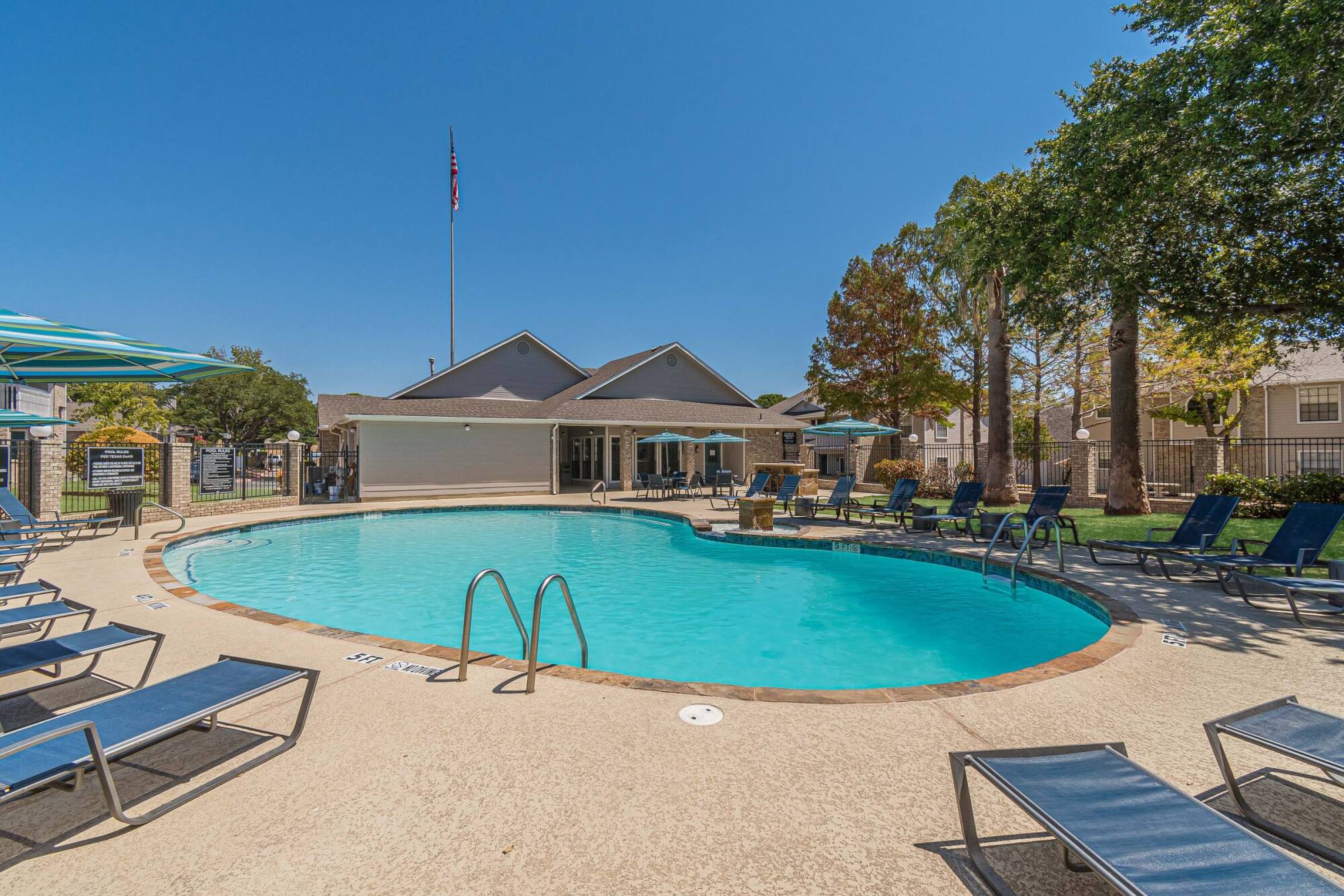 Keystone Apartments swimming pool with clubhouse and American flag in Killeen TX